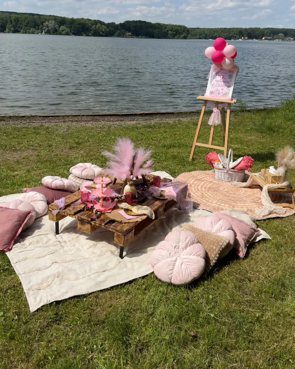 Boho posezení u jezera: nízký stůl z palet, růžové polštáře, deky a dekorace